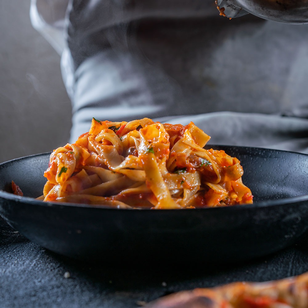 שף מחזיק פסטה ברוטב עגבניות