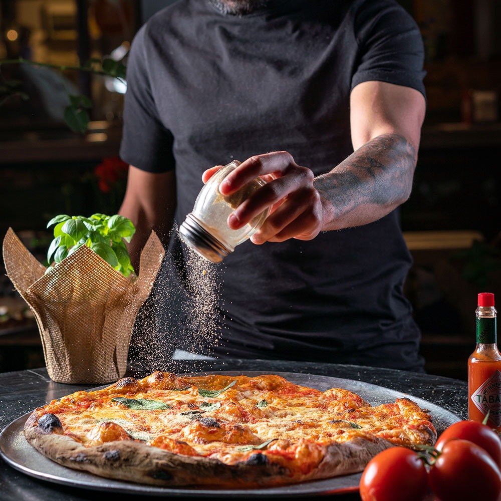 בחור מפזר פרמזן על פיצה