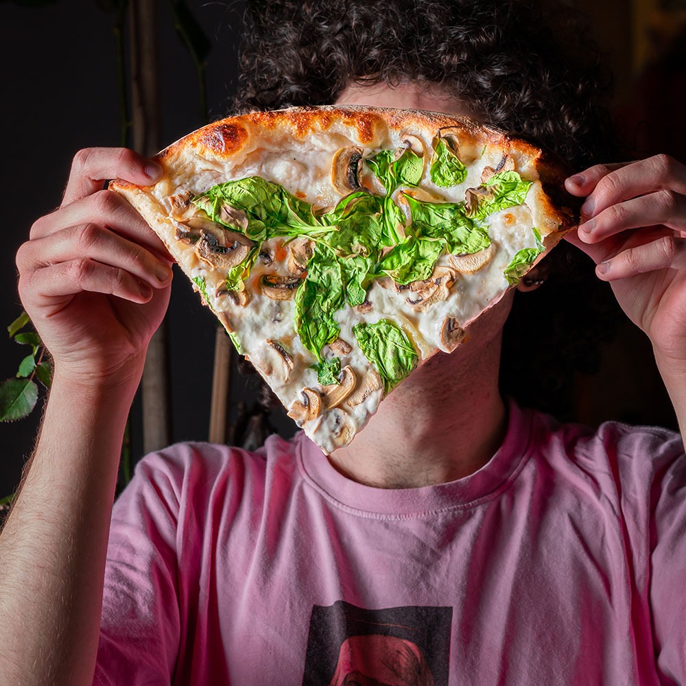 בחור מסתיר את פניו עם משולש פיצה